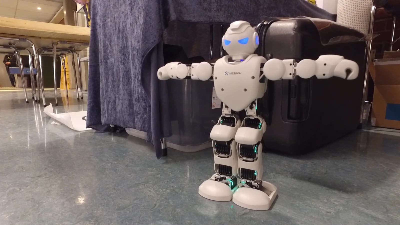 UBTECH Alpha 1PRO humanoid robot standing with arms outstretched in a room.