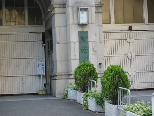 Entrance to Japan's Ministry of Finance building with Japanese characters on a sign.