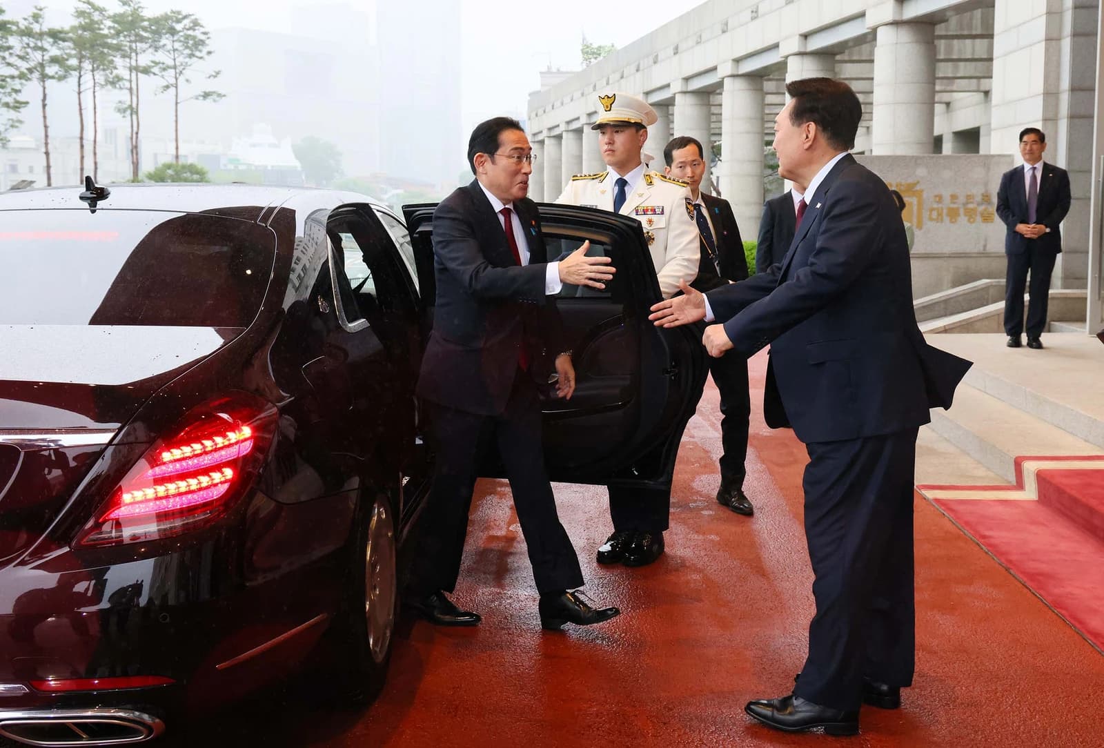 Japanese Prime Minister Fumio Kishida greeting South Korean President Yoon Suk-yeol by a car.