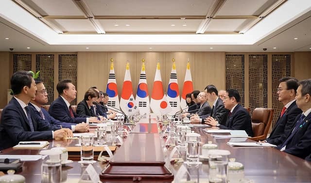 Heads of state and their delegations meeting around a long table.