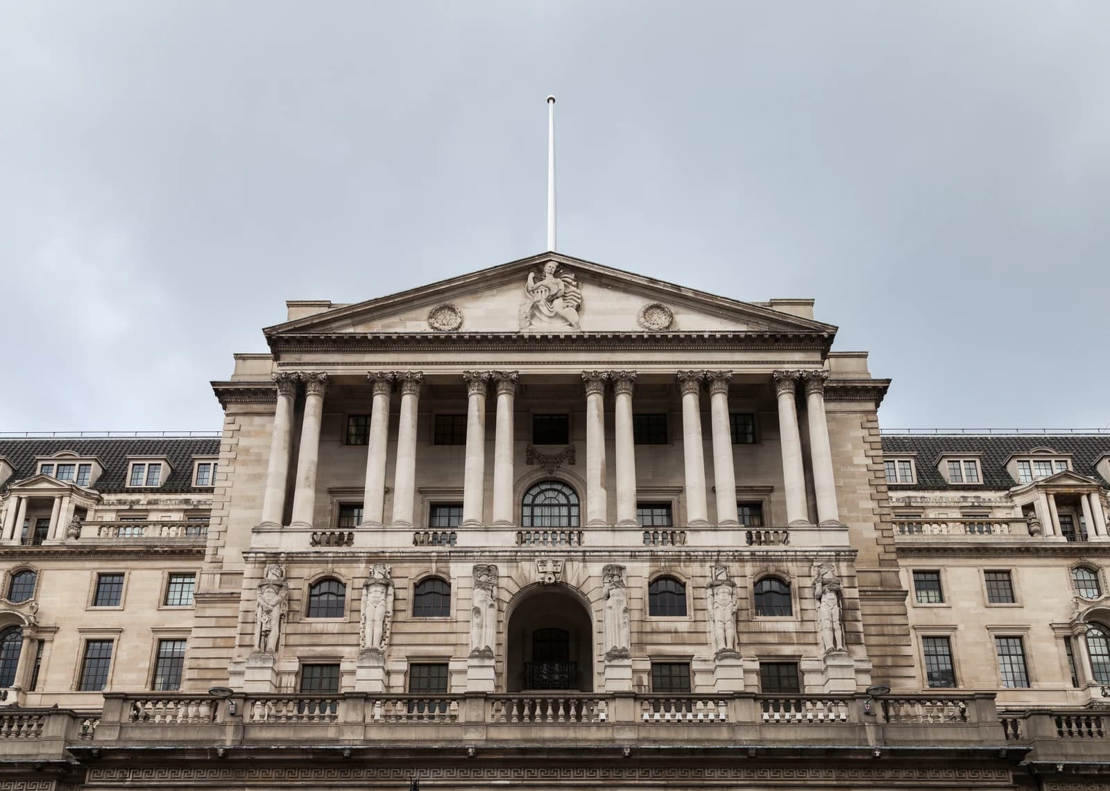 Bank of England building with classical architecture, columns, and a flagpole on the roof.