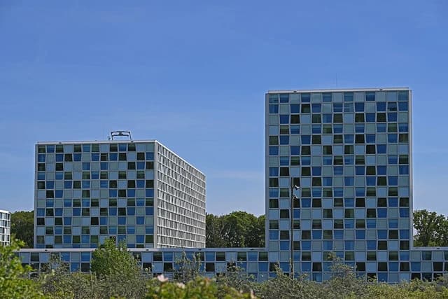 The Hague International Criminal Court building, with a grid-patterned facade, under blue sky.