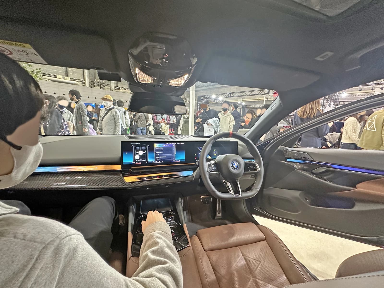 Interior of a BMW XM (G09) on display at an auto show, with attendees visible outside.