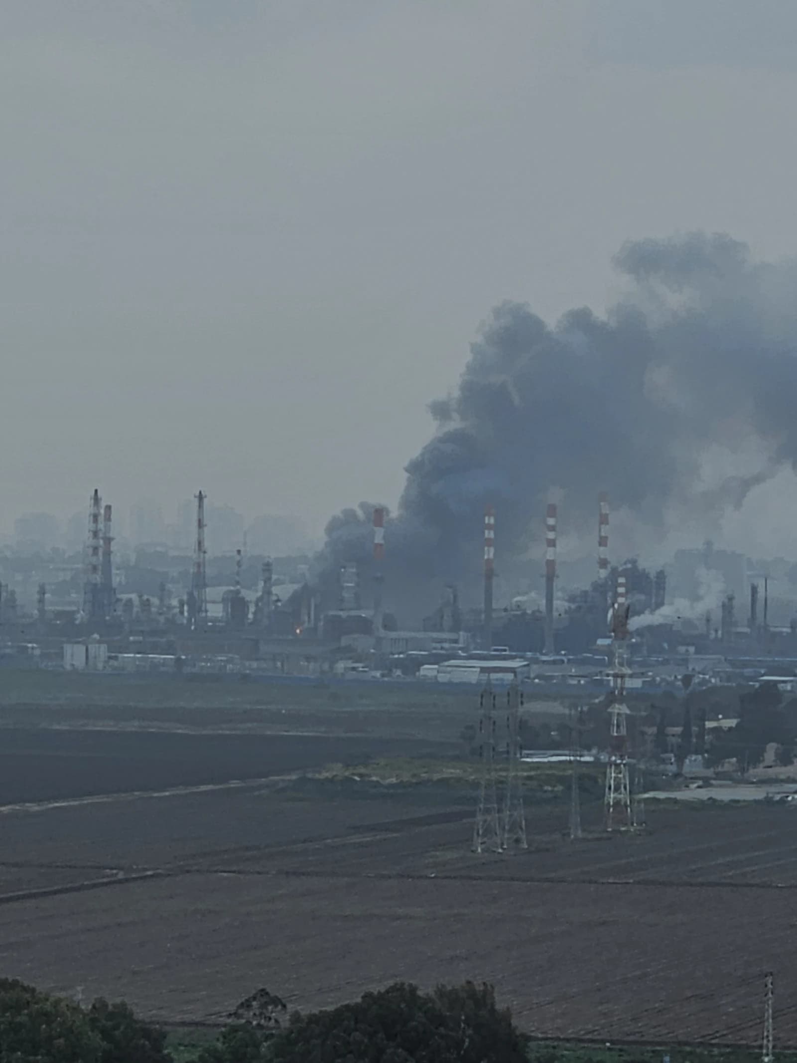 Smoke rising from oil refineries in Haifa Bay after a missile interception.