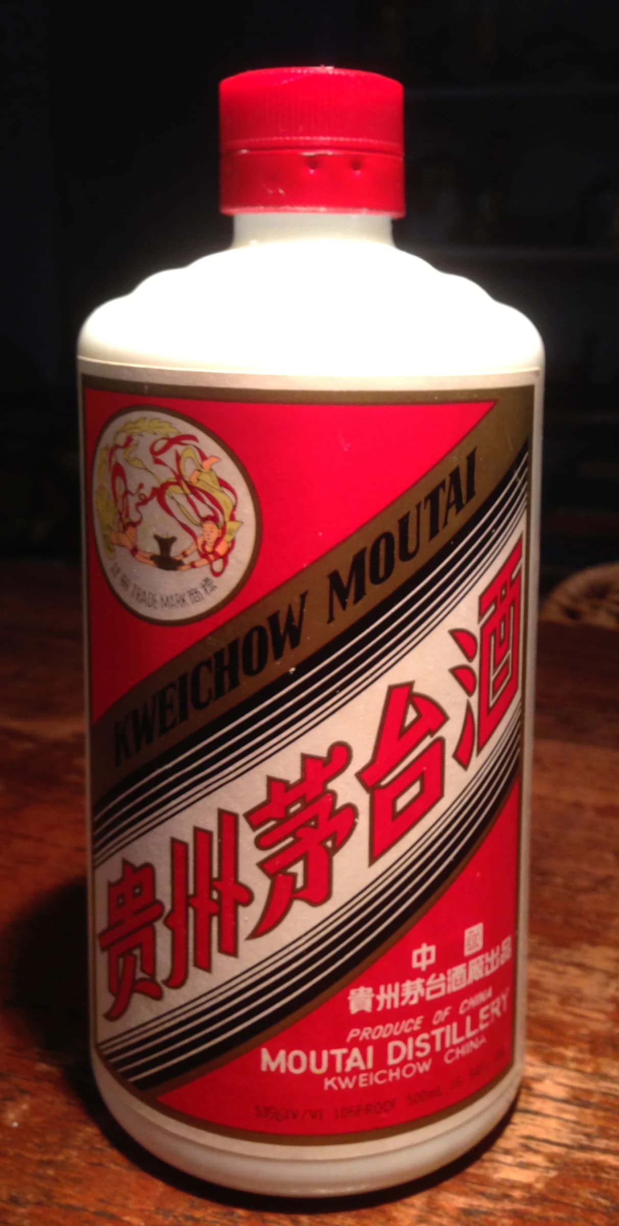 A white bottle of Kweichow Moutai with a red and gold label on a brown surface.