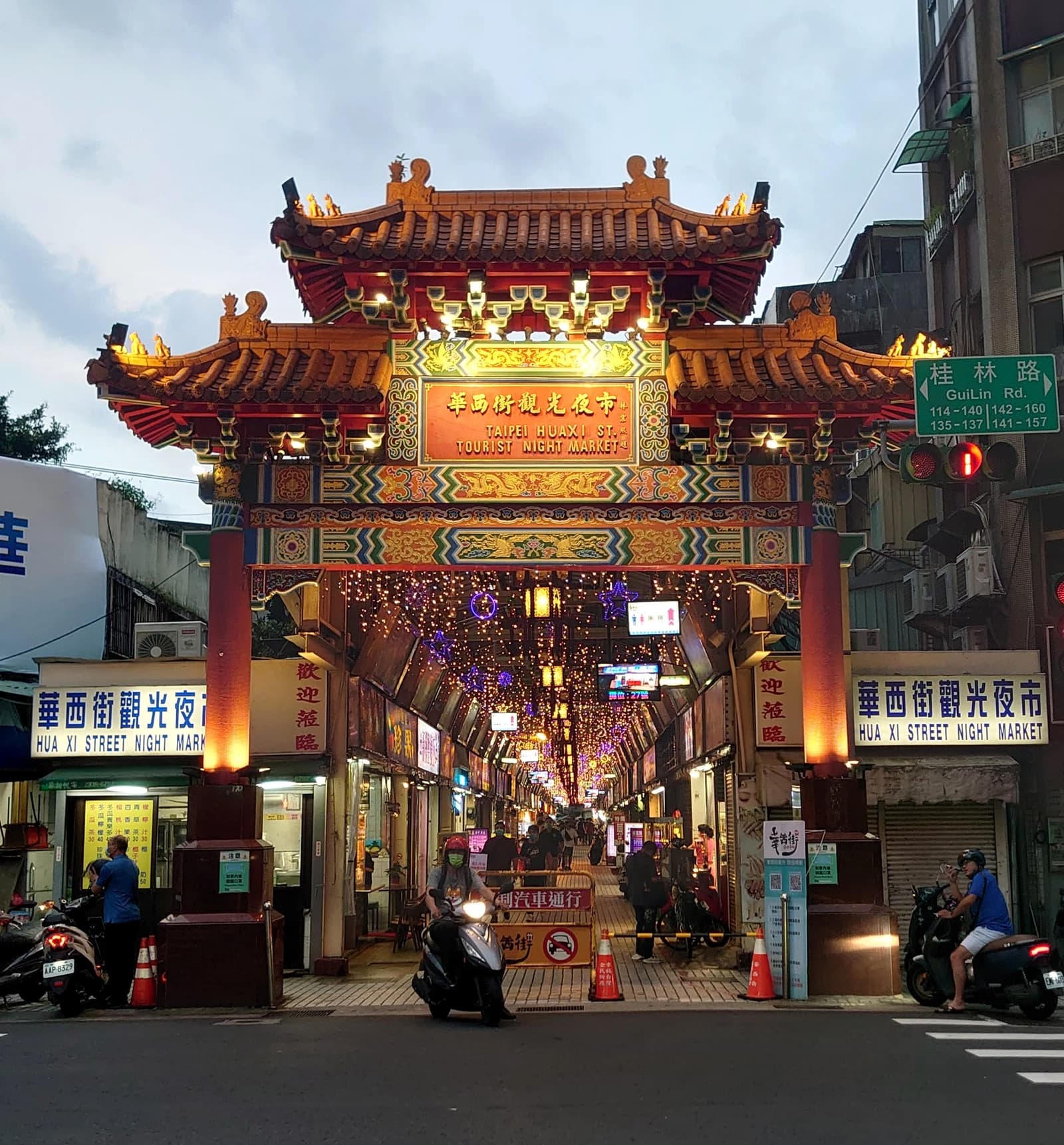 The ornate entrance gate of Huaxi Street Tourist Night Market in Taiwan, with market stalls visible inside.