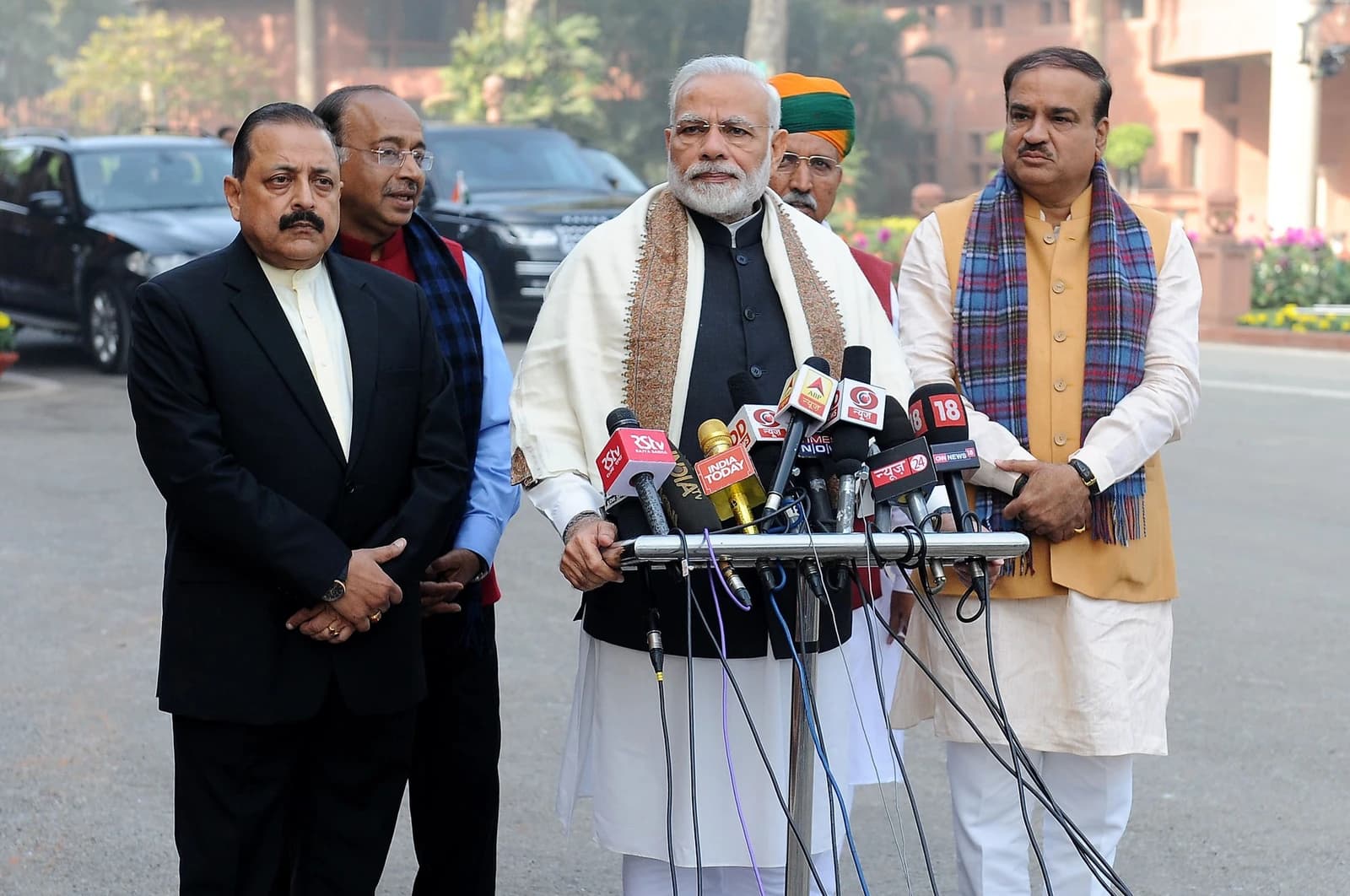 Narendra Modi, Prime Minister of India, speaking at a podium with multiple microphones.