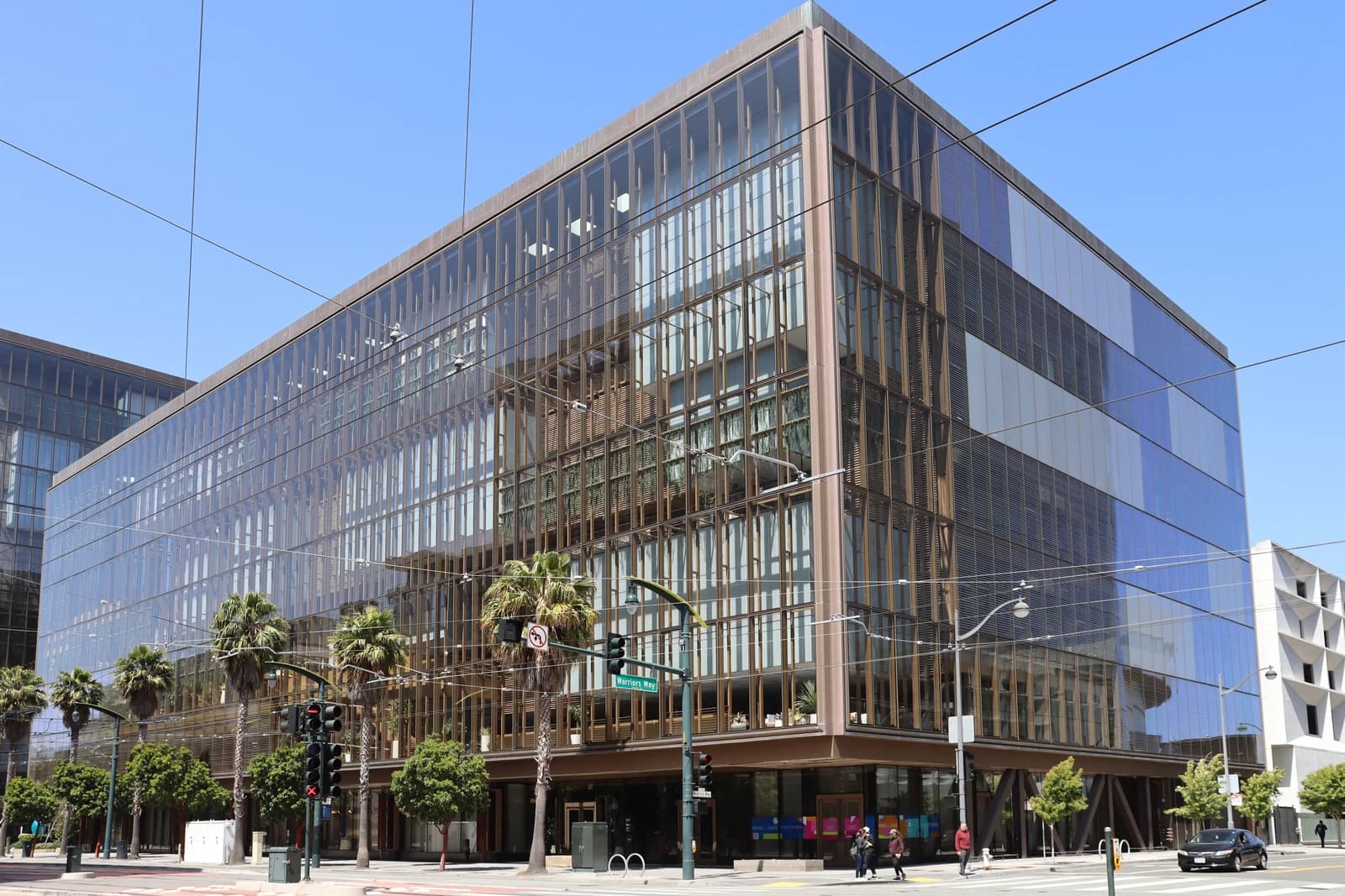 Exterior view of a large, modern glass office building on a sunny day.