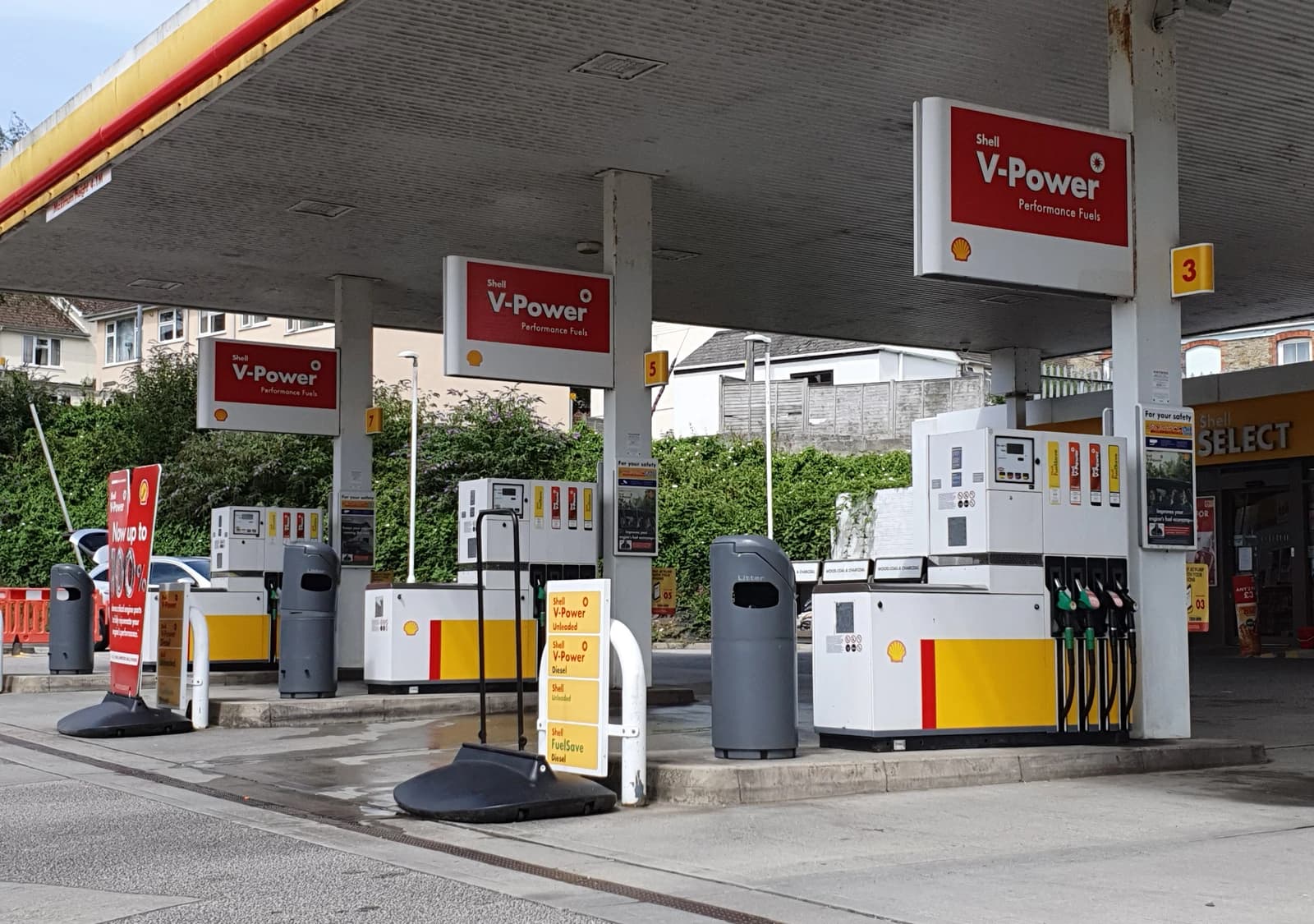 Multiple fuel pumps under a canopy at a Shell petrol station.