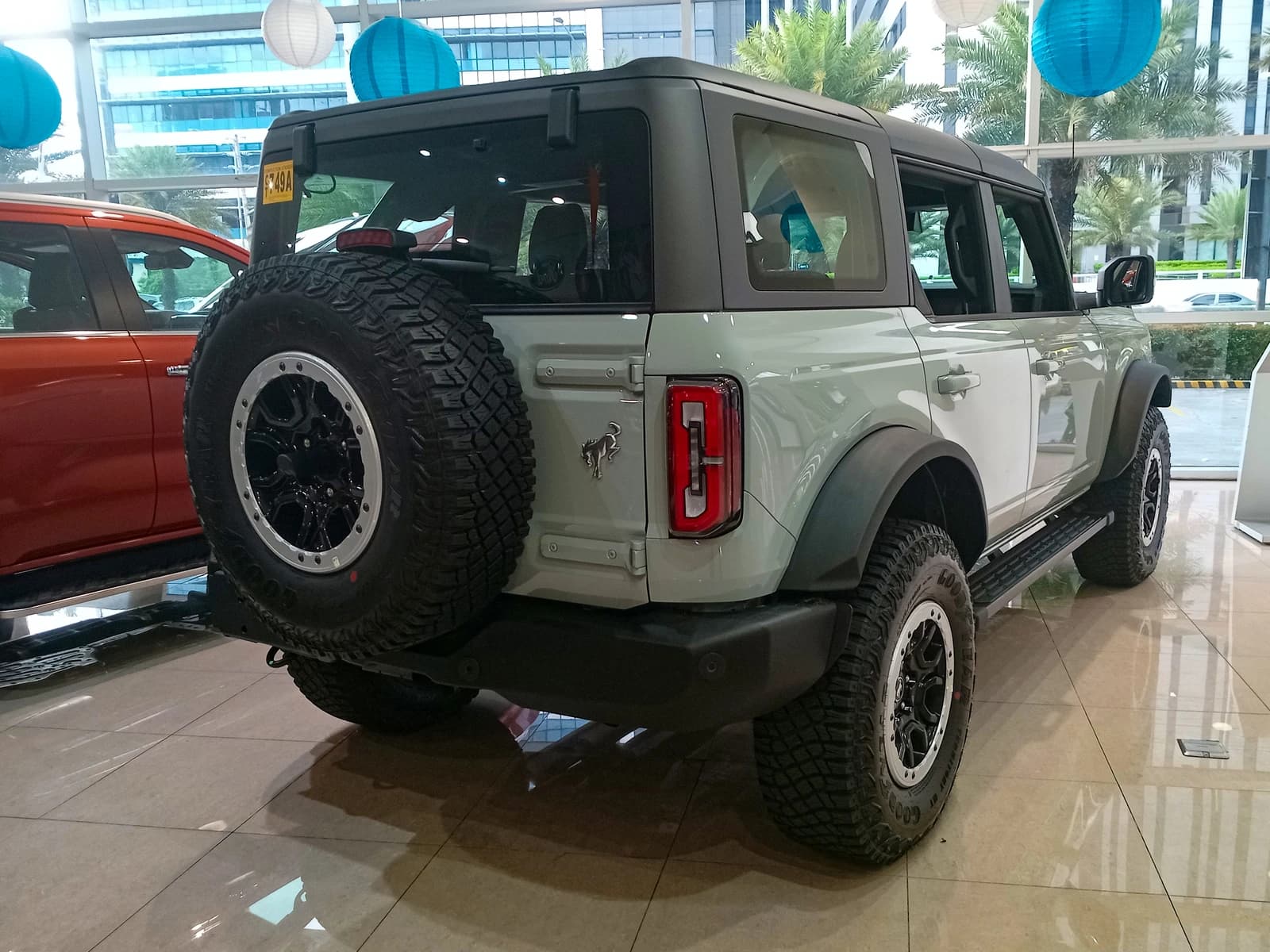 2024 Ford Bronco Outer Banks V6 in Cactus Gray, rear right view in a showroom.