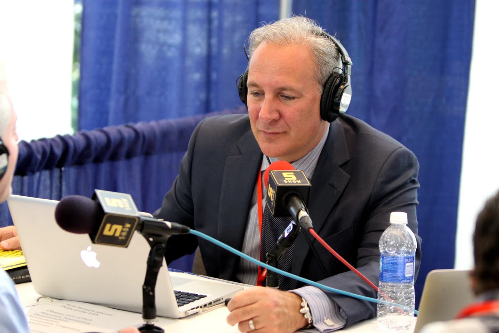 Peter Schiff, American stockbroker and financial commentator, speaks into microphones at a table.