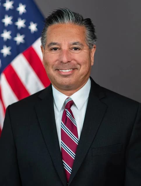 Jaime Lizarraga, SEC Commissioner, smiling in an official portrait with a flag background.