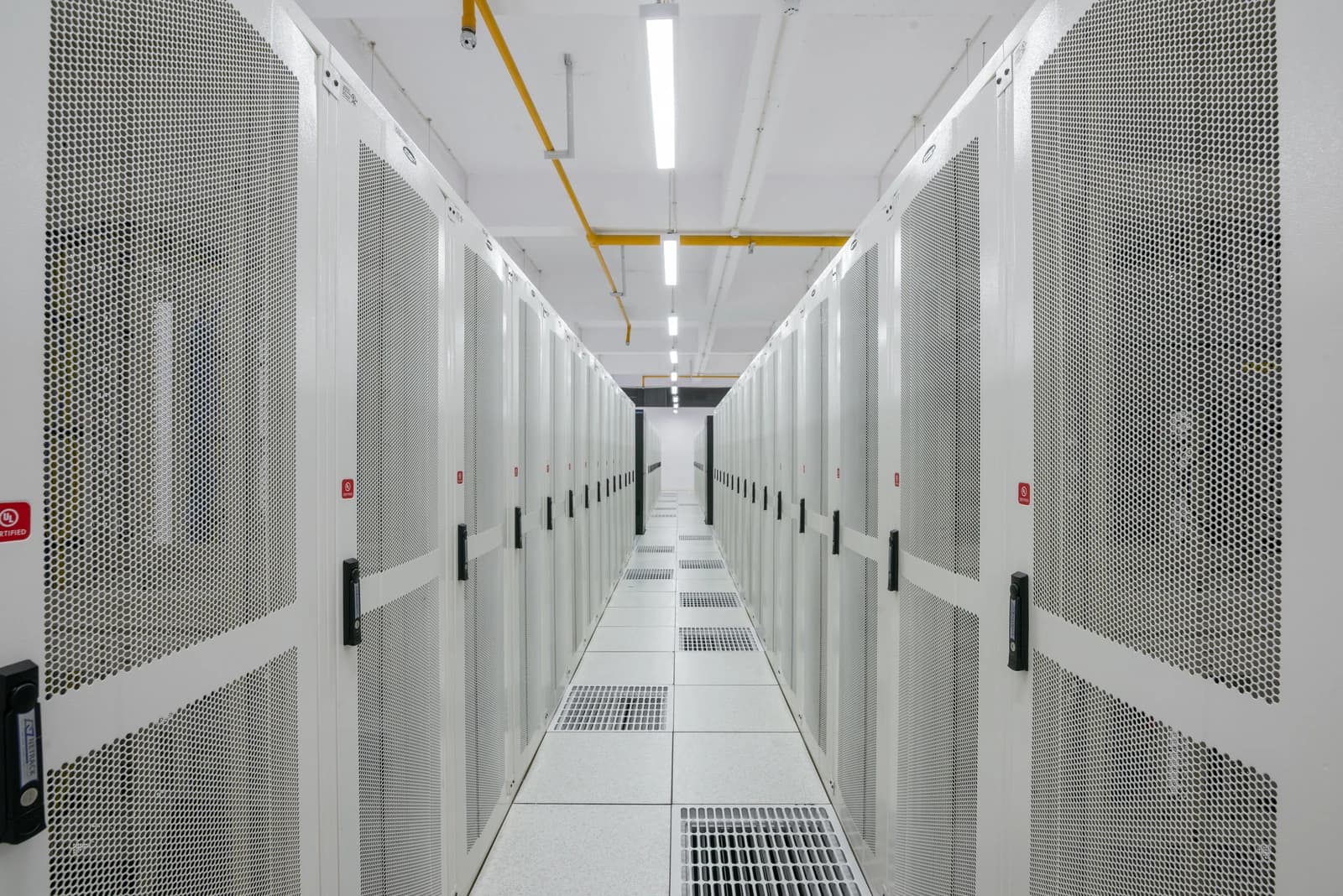 An aisle of white server racks stretches into the distance inside a modern data center.