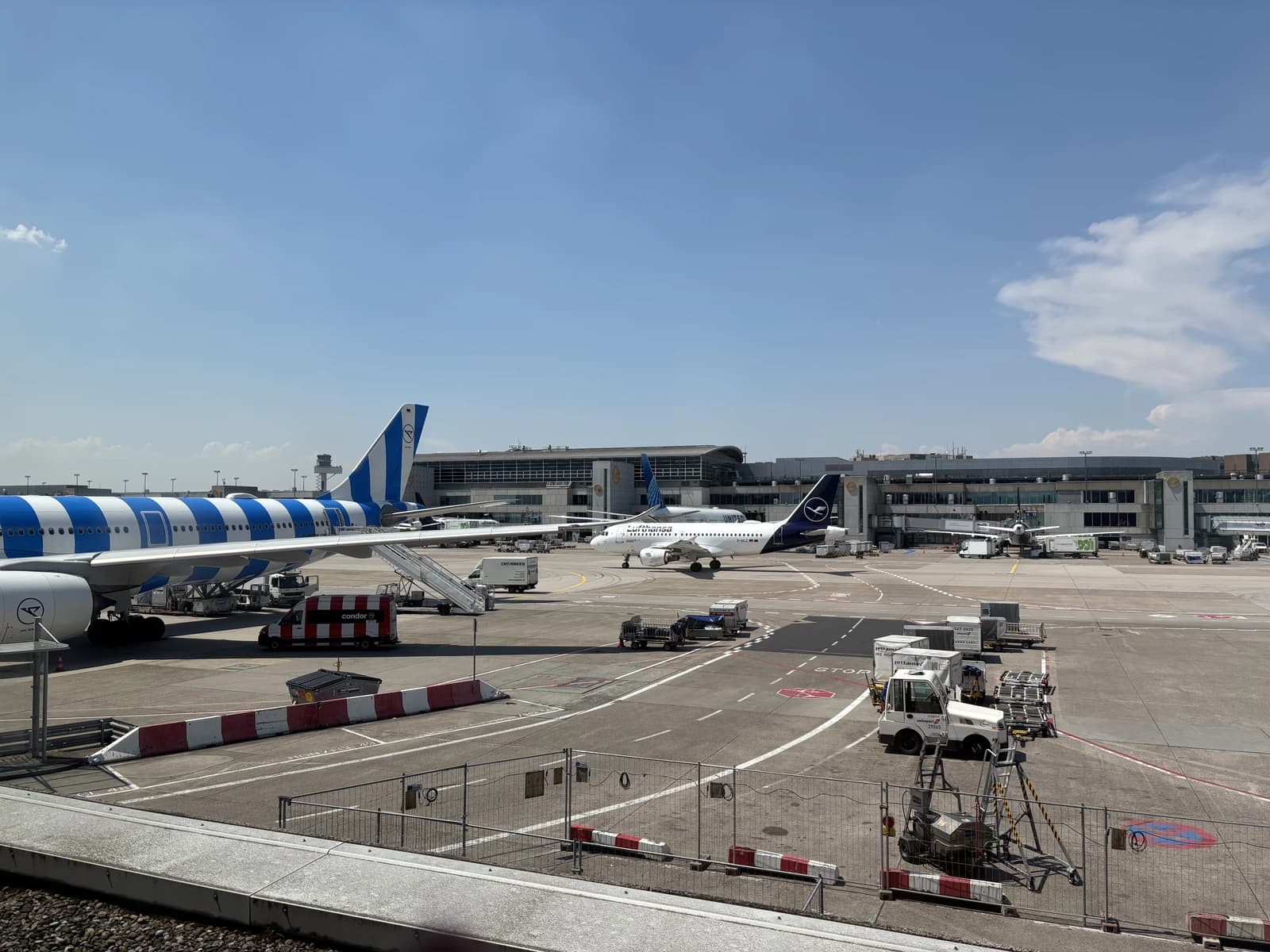 Ground crew vehicles near passenger airplanes at Frankfurt Airport tarmac.