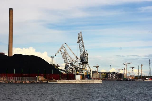 Cranes and a large pile of coal at Hanasaaren laituri in Helsinki, Finland.