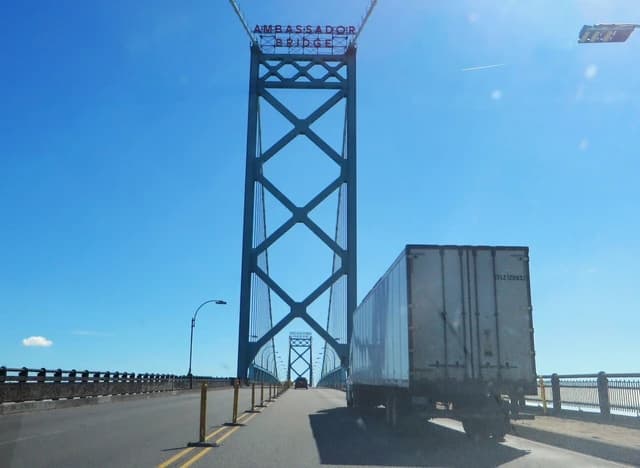 Truck driving across the Ambassador Bridge under a clear blue sky.