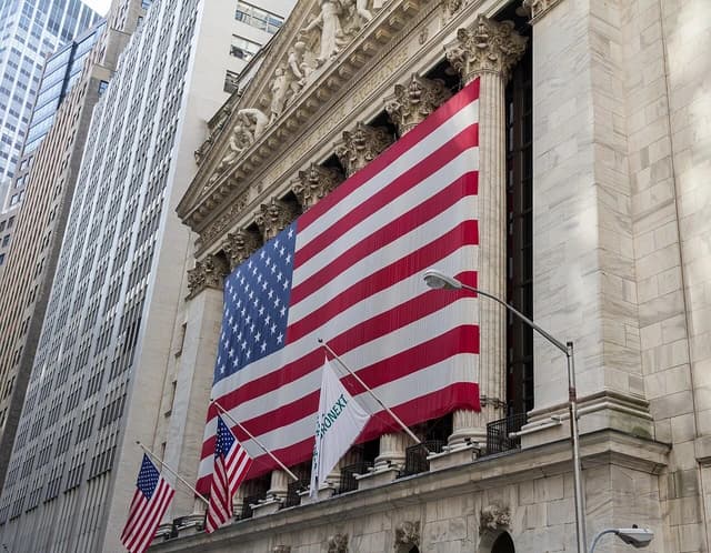 New York Stock Exchange building on Wall Street, draped with a large American flag.