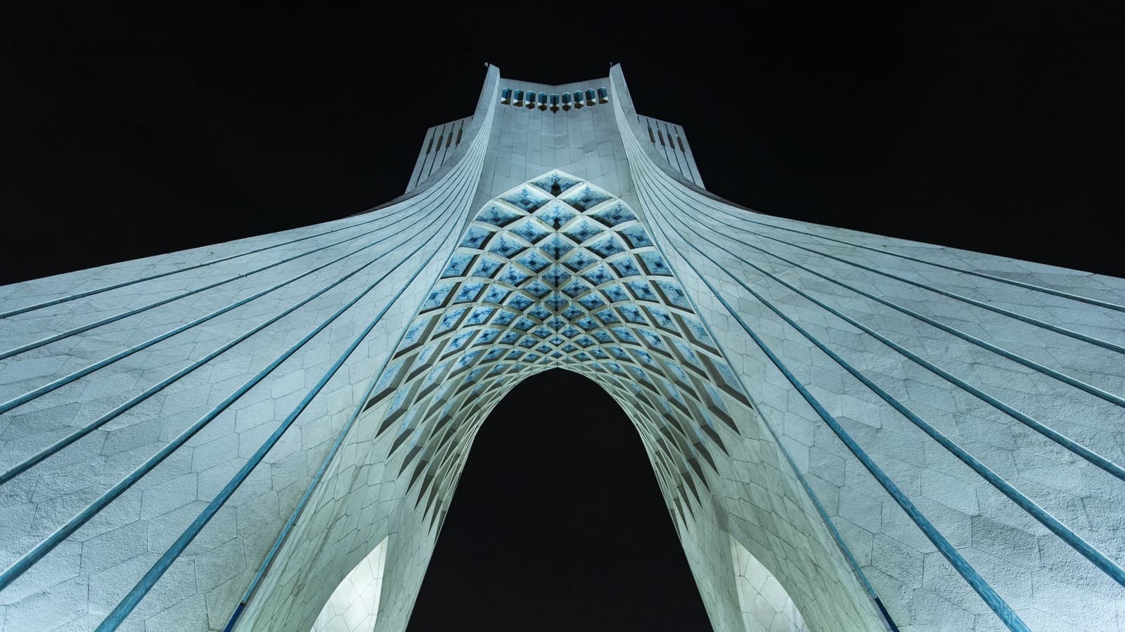 Azadi Tower, a monument in Tehran, Iran, seen from a low angle at night.