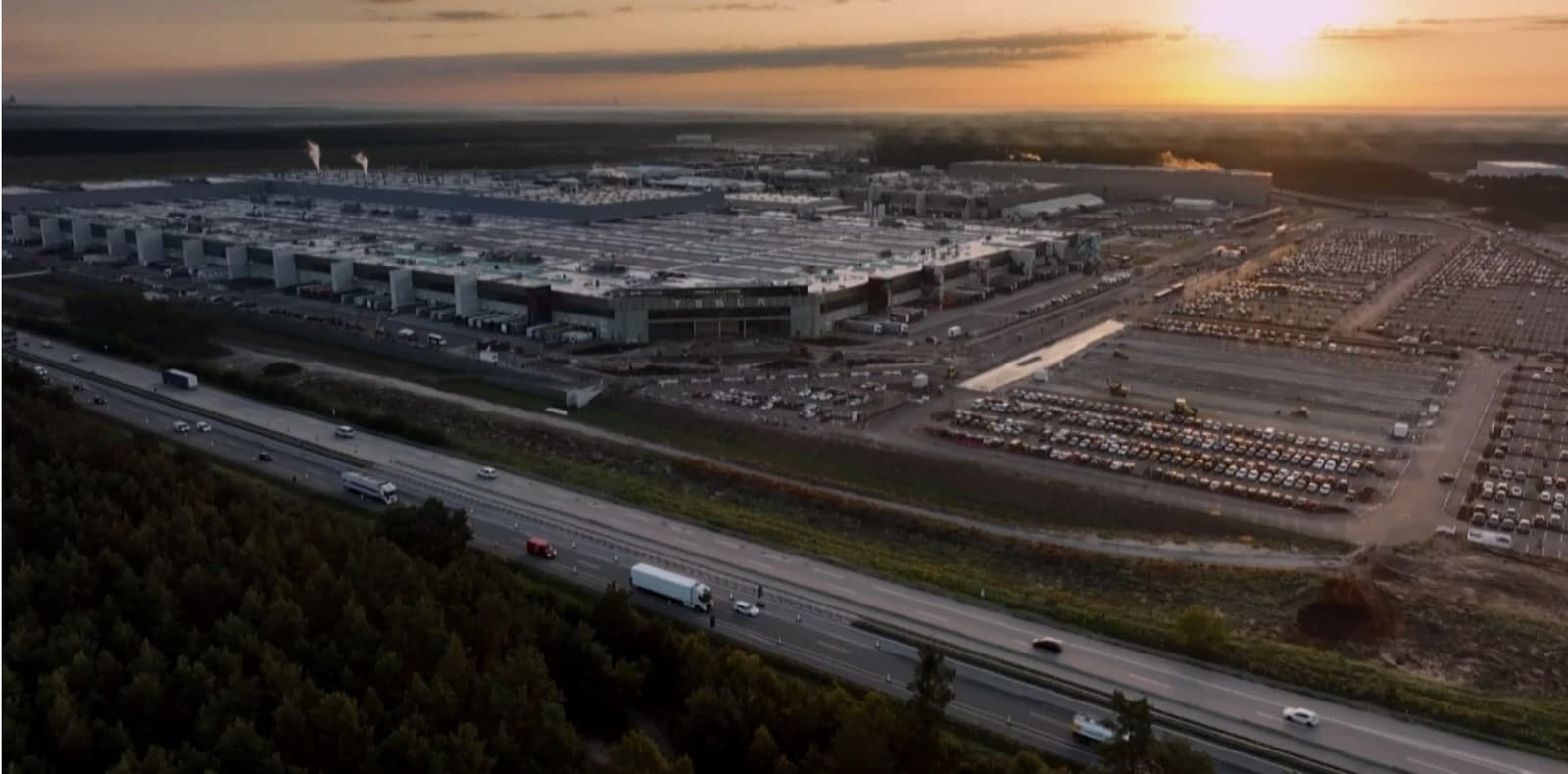 Aerial view of Tesla Gigafactory Berlin-Brandenburg with highway at sunset.
