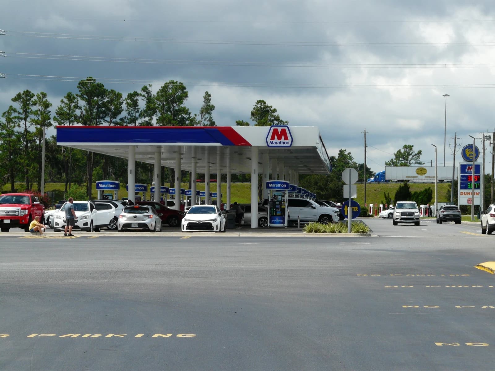 Cars parked at a Marathon gas station in Live Oak, Florida, with people pumping gas.