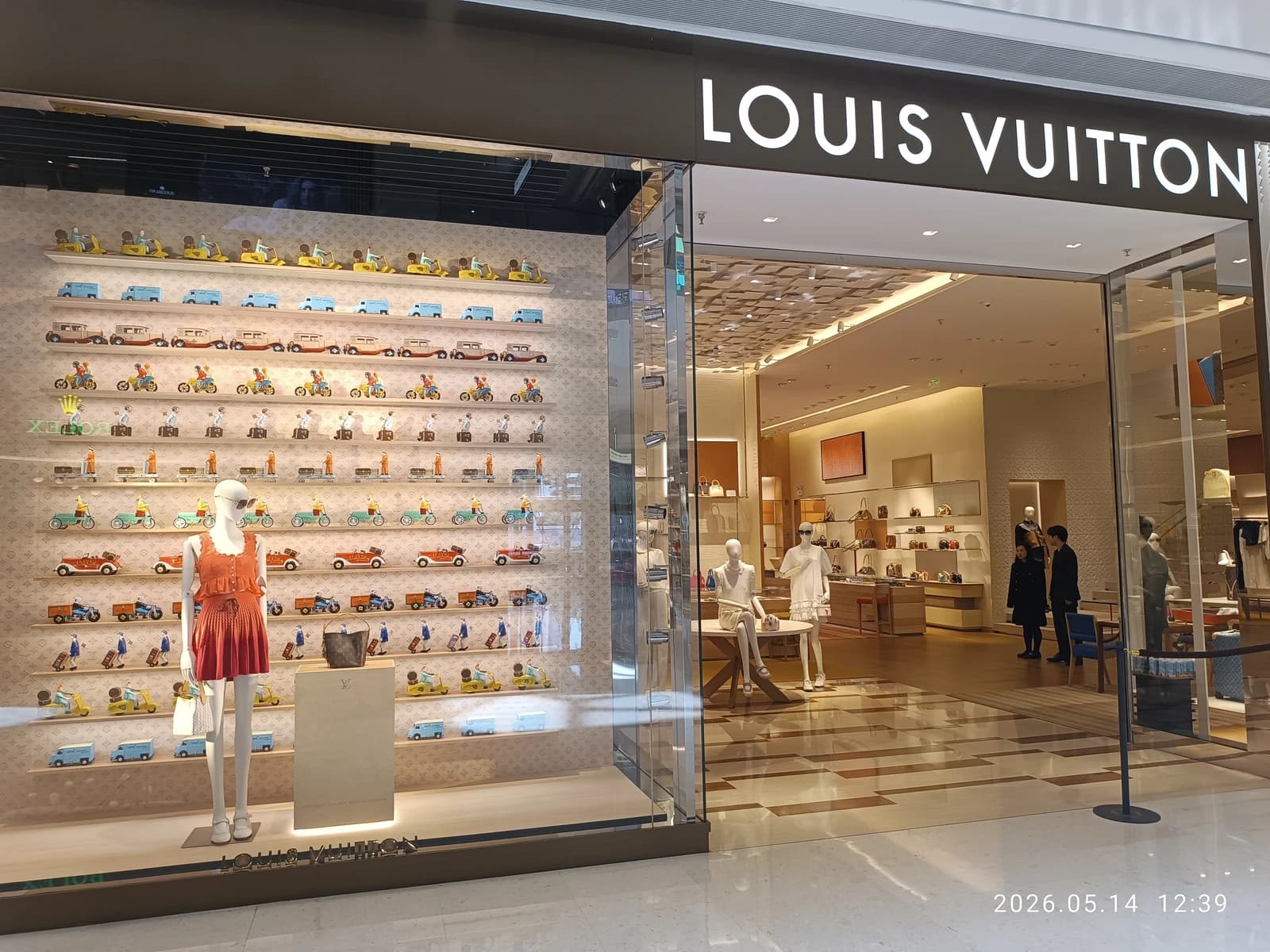 Louis Vuitton store entrance and display window with mannequins and products.