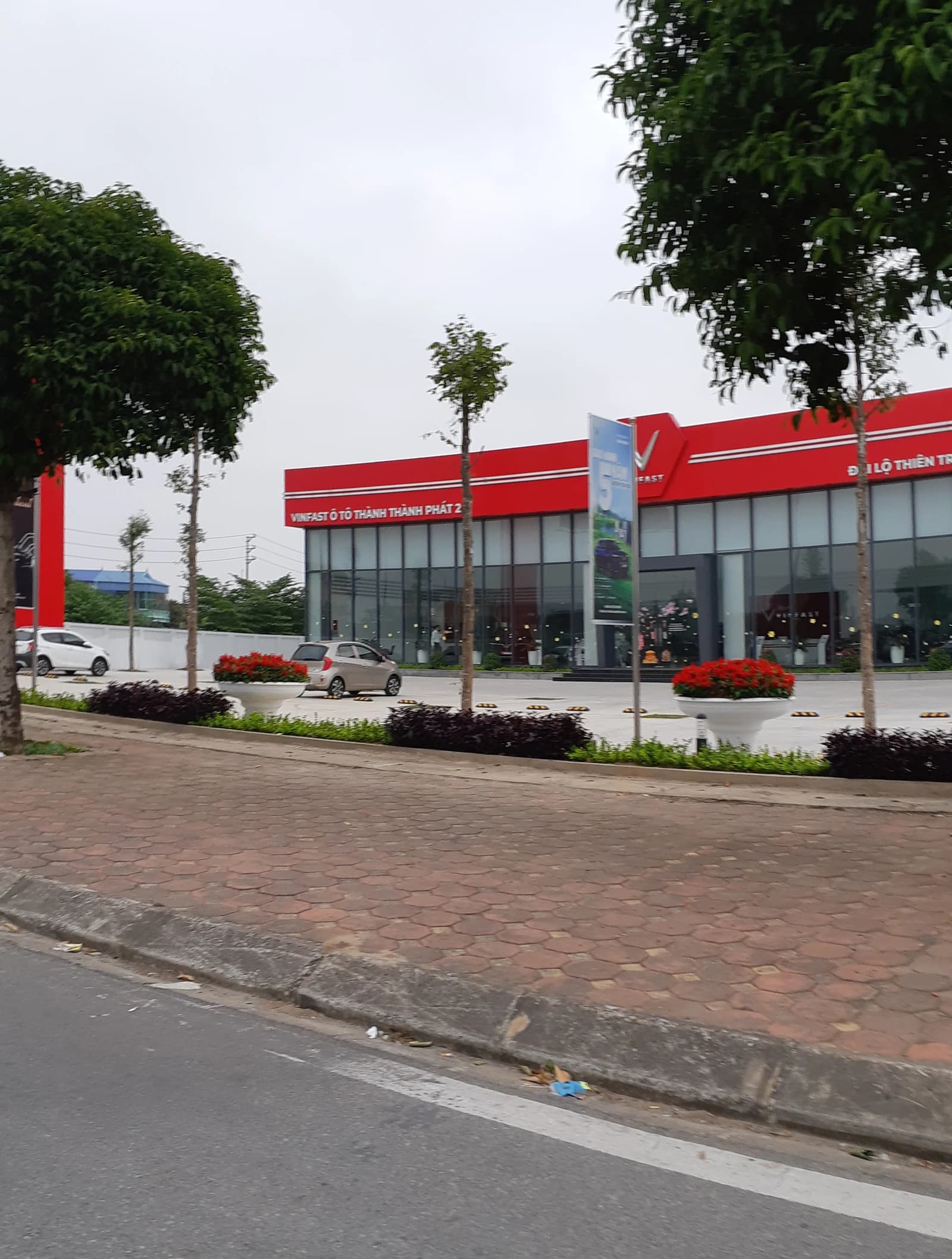VinFast car dealership building with red facade and glass windows on a cloudy day.