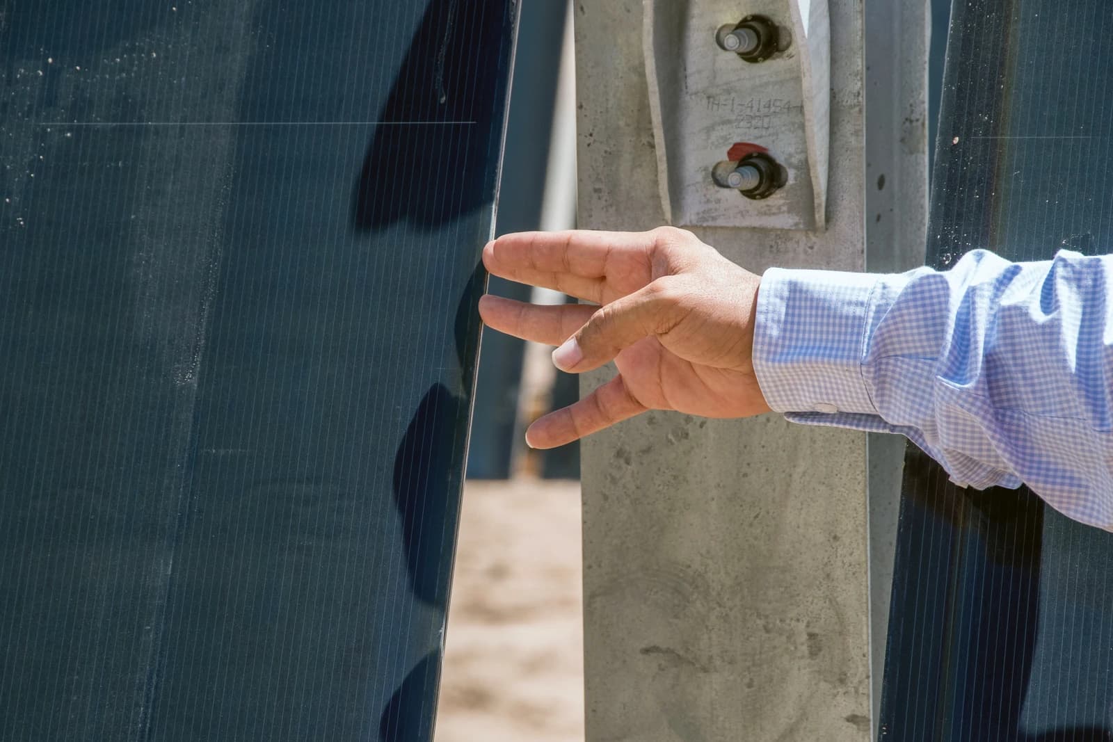 A person's hand touches a solar panel in an outdoor setting.