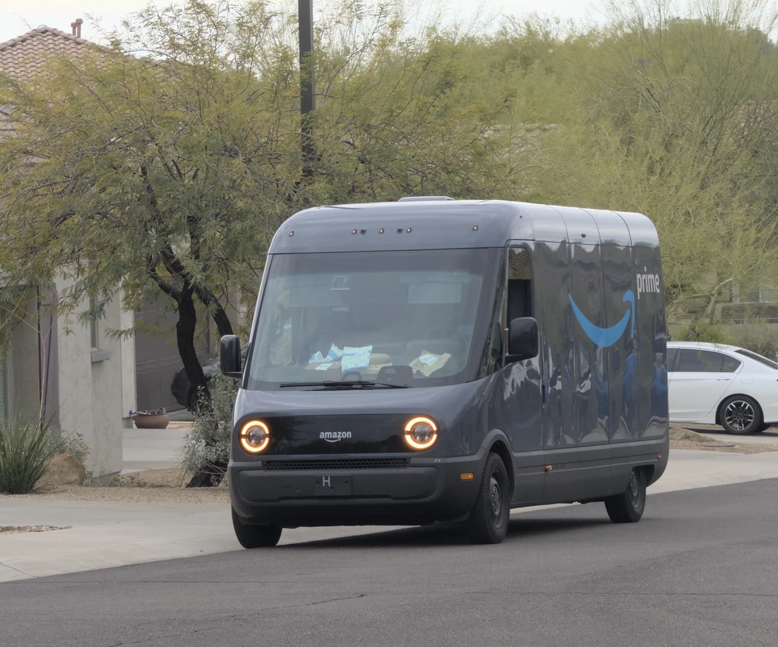 Amazon electric delivery vehicle driving on a residential street.