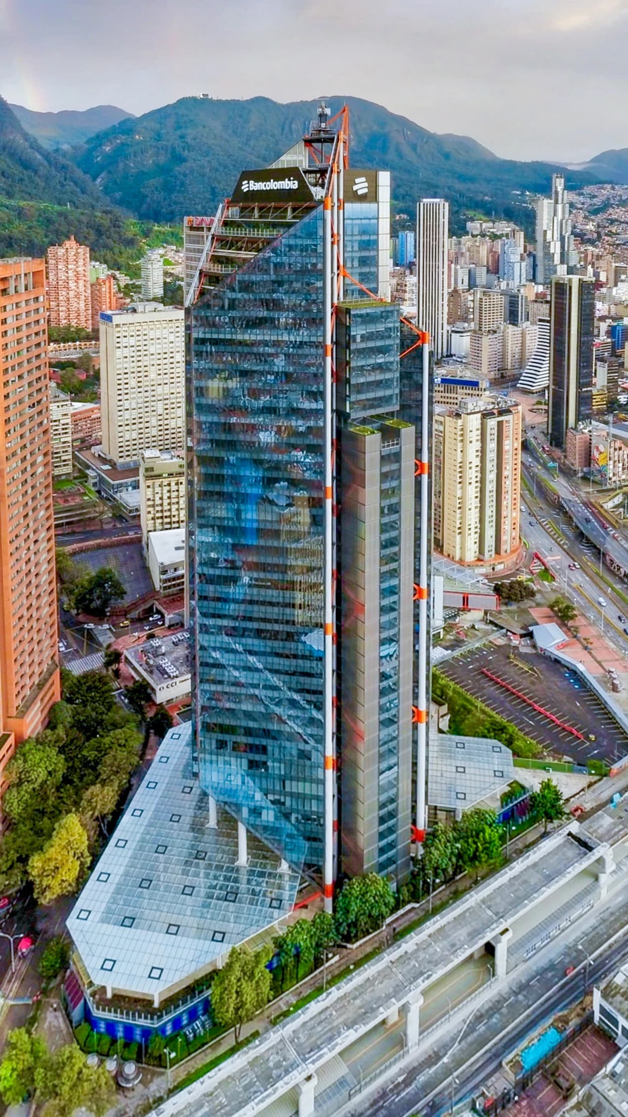Aerial view of the Bancolombia financial building in a city with mountains in the background.