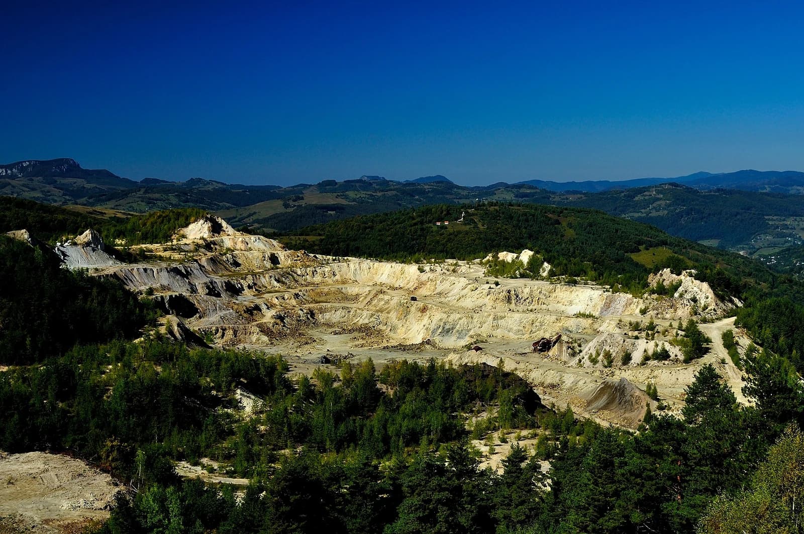 Aerial view of Cetate open-pit gold mine with visible terraced excavations.