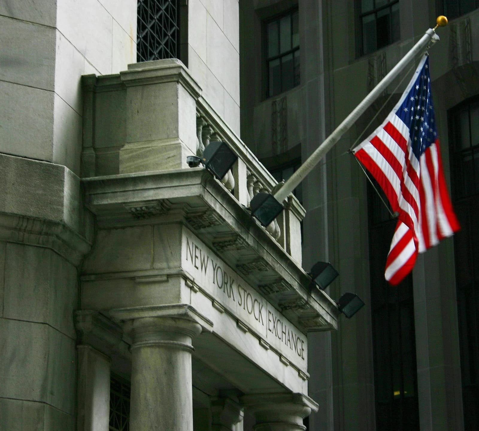 Main entrance of the New York Stock Exchange building with an American flag flying.