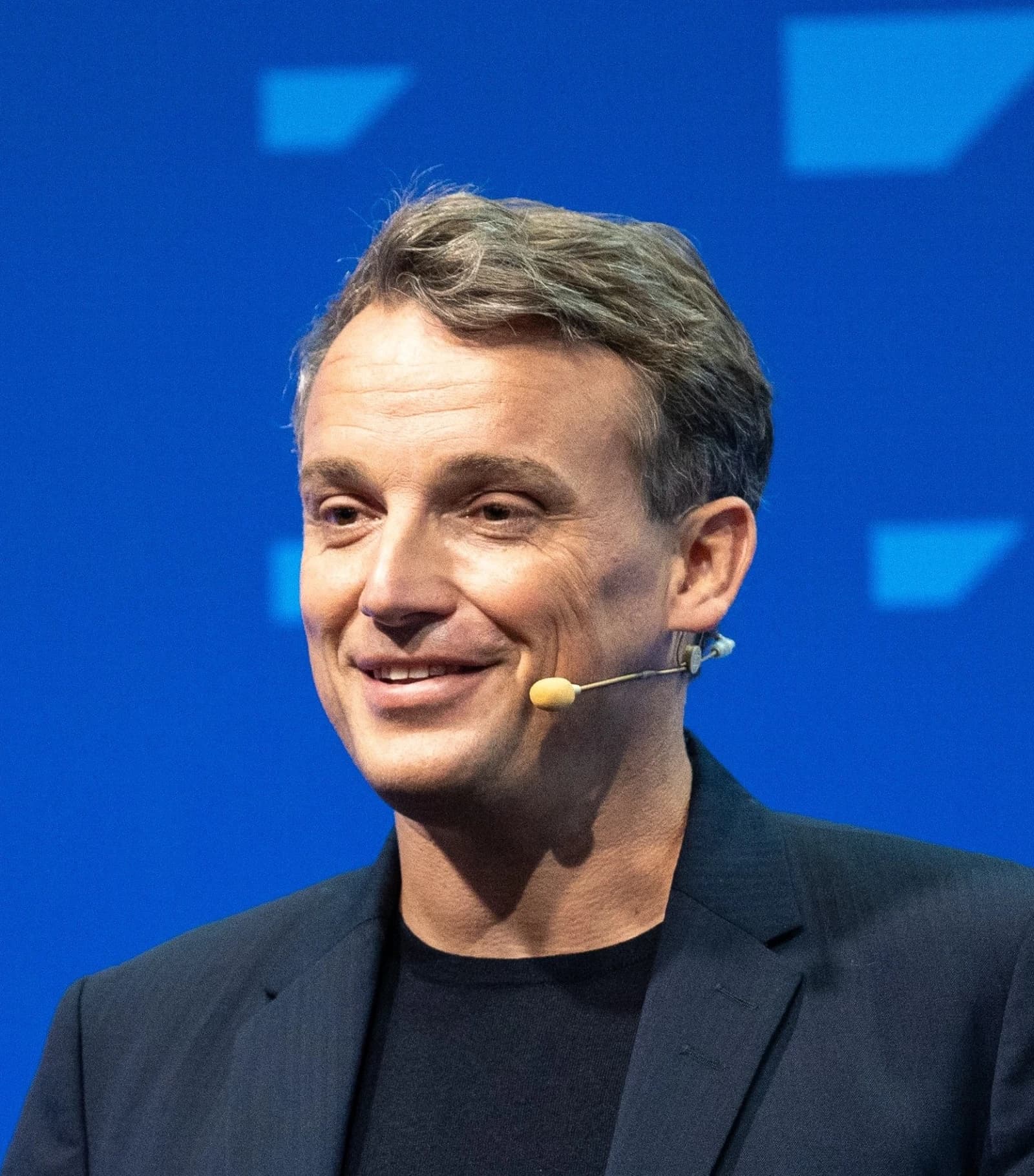 Christian Klein, CEO of SAP, smiles while speaking into a headset microphone.