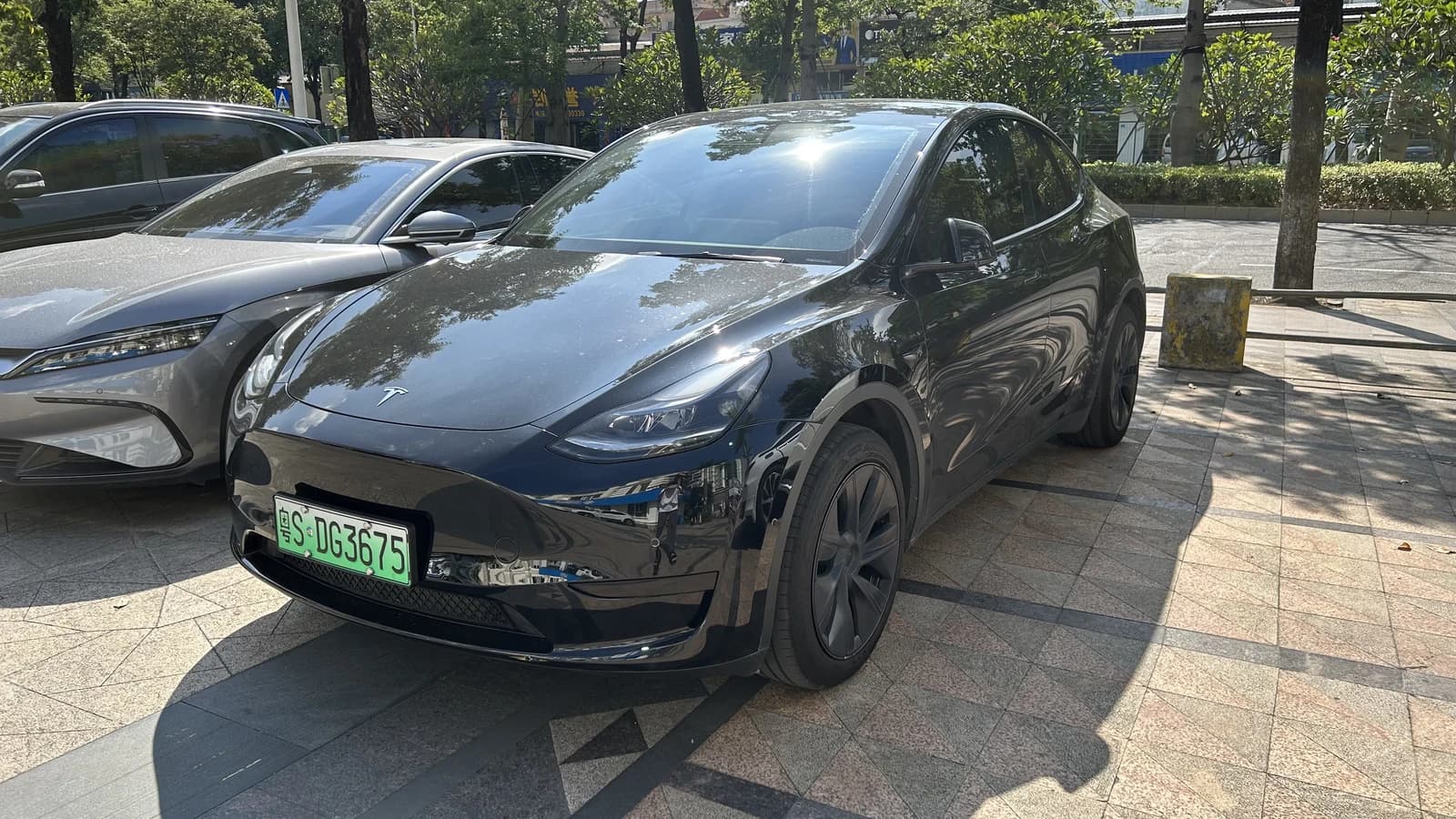 Black Tesla Model Y electric vehicle with a green Chinese license plate.