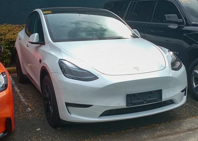 A white 2024 Tesla Model Y Long Range FWD parked in an outdoor lot.