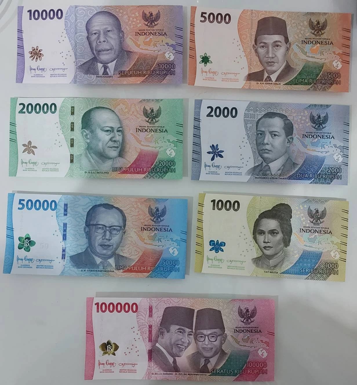 Several Indonesian Rupiah banknotes of different denominations are arranged on a surface.