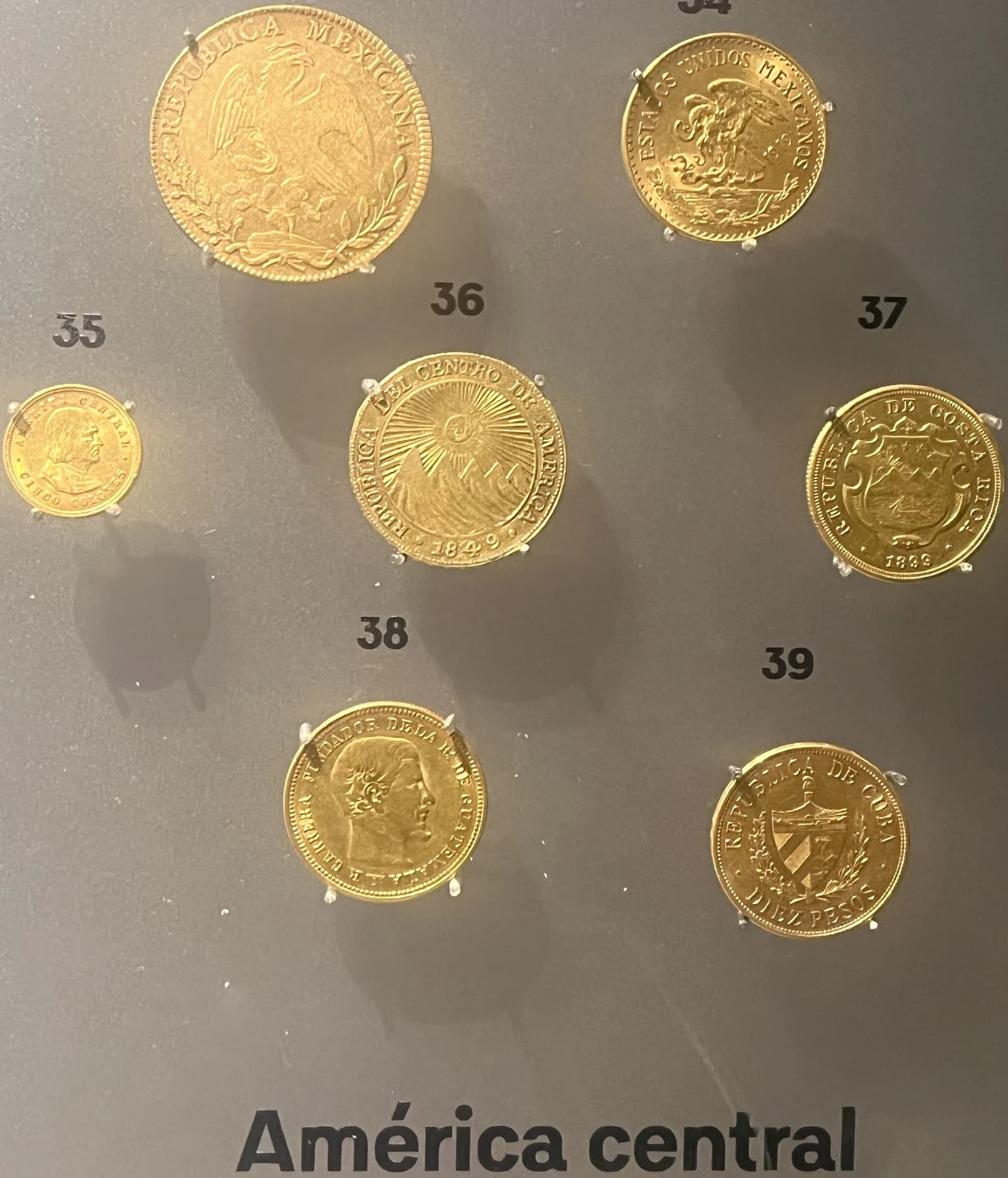 Collection of various gold coins from Central American countries displayed.
