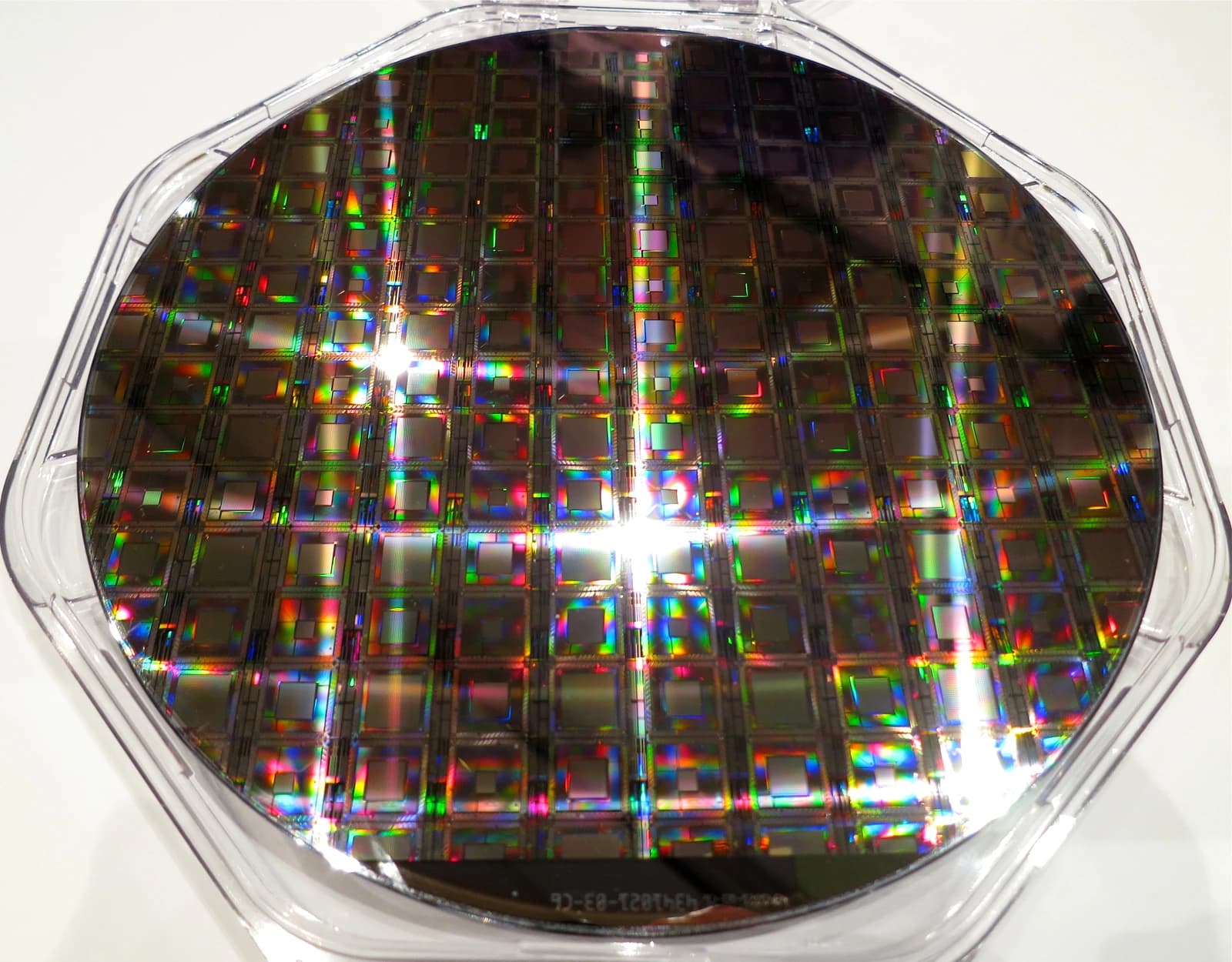 Close-up view of a D-Wave quantum processor wafer with iridescent reflections on its surface.
