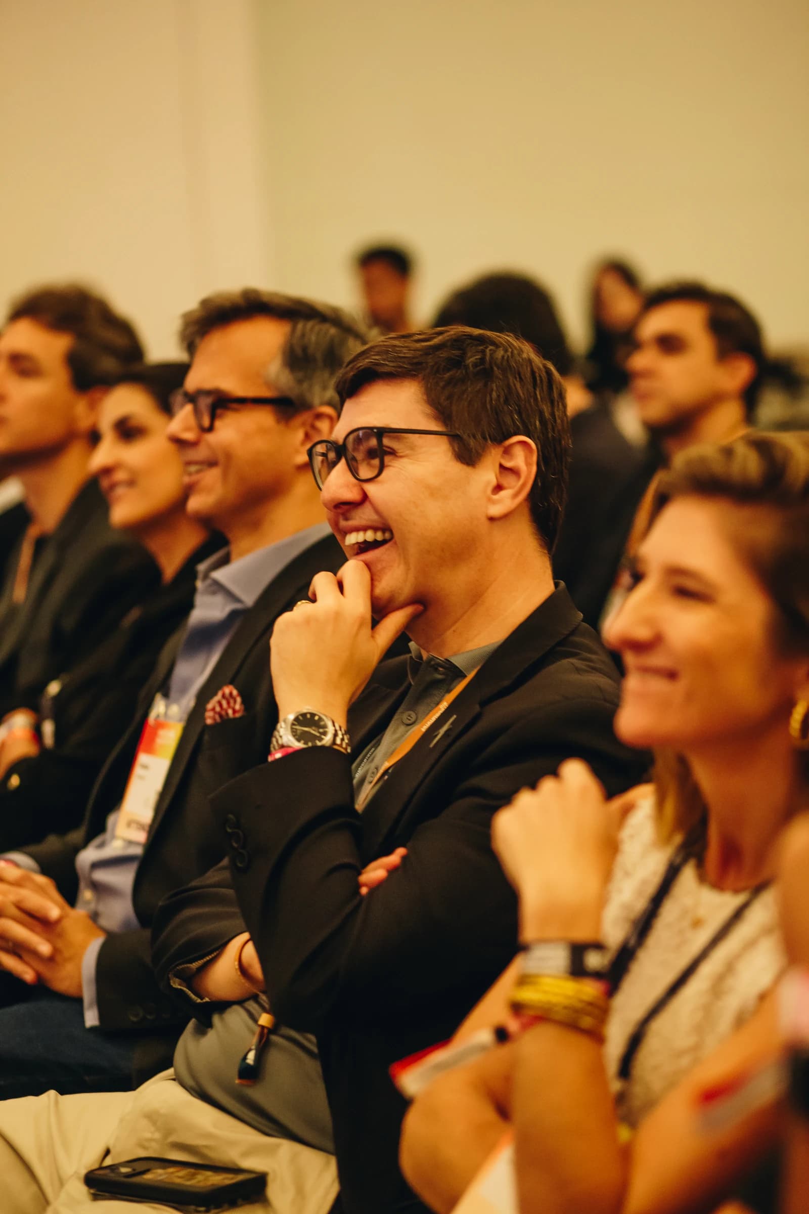 Man with glasses smiling in an audience at a conference.