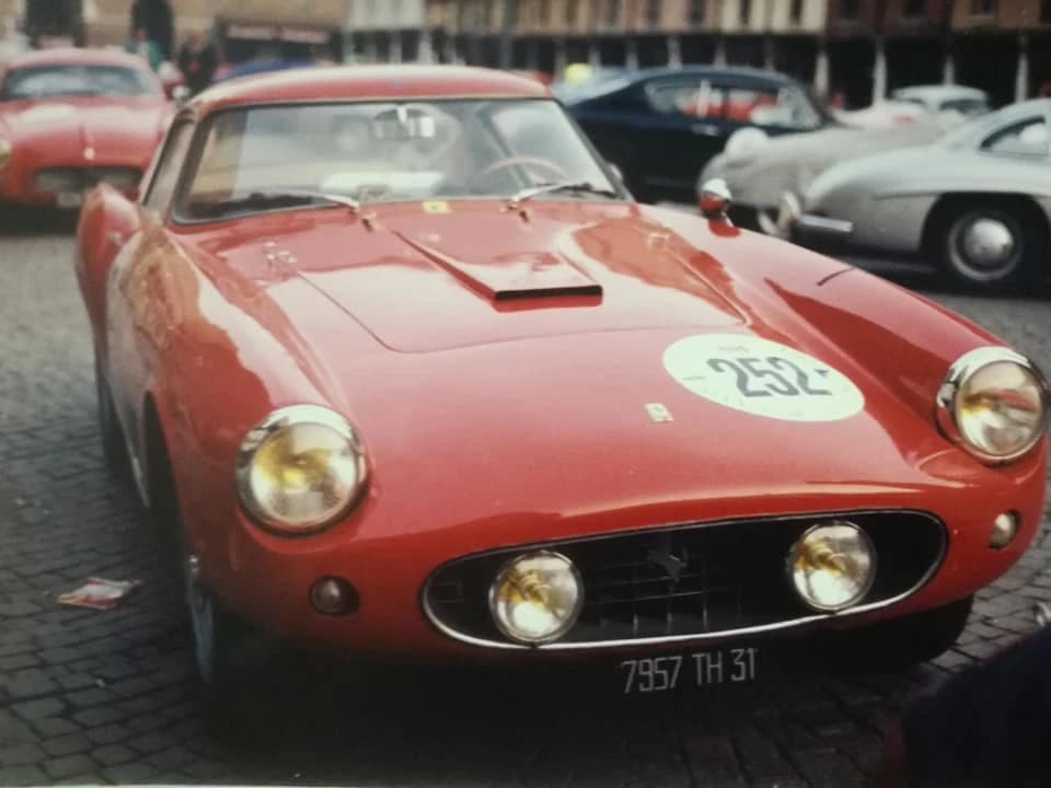 Vintage red Ferrari 250 TdF car number 252 parked on cobblestones.