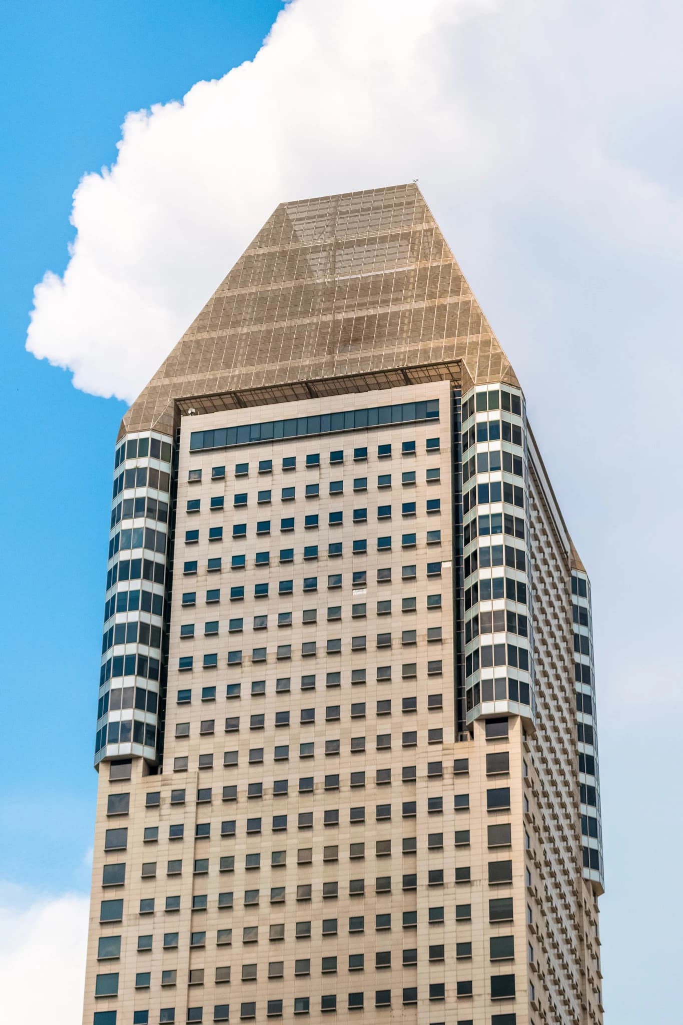 Millenia Tower, a corporate high-rise building, stands against a blue sky with clouds.