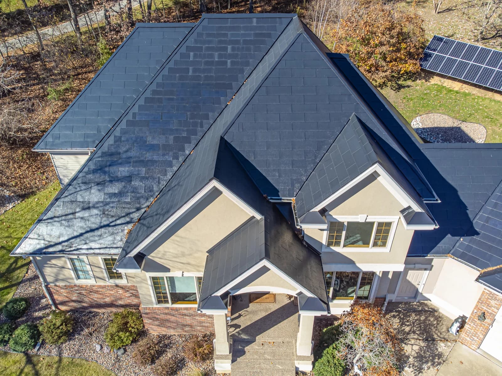 An aerial view of a residential house with a dark grey Tesla Solar Roof.