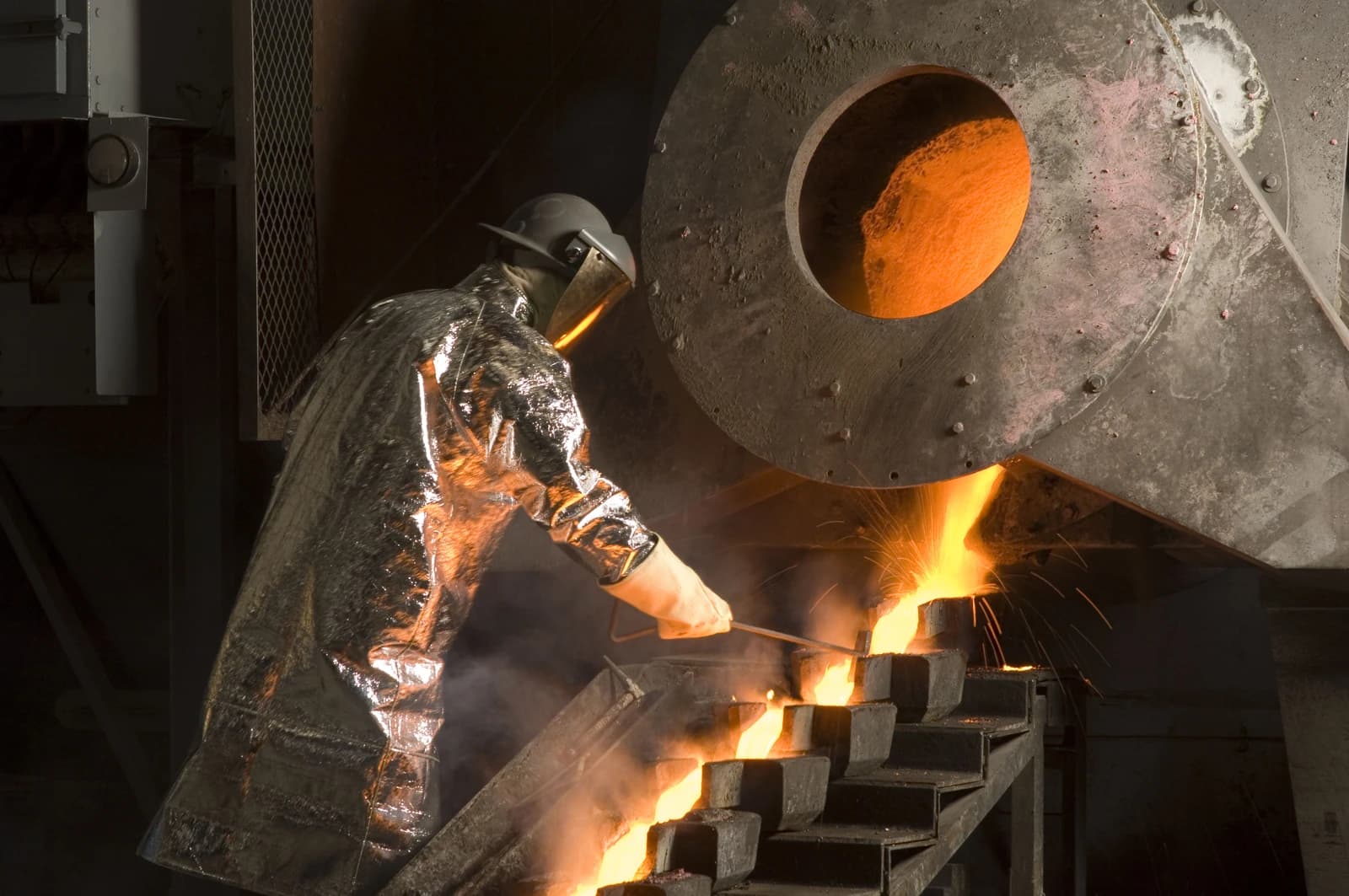 Worker pouring molten gold into molds at a gold mine.