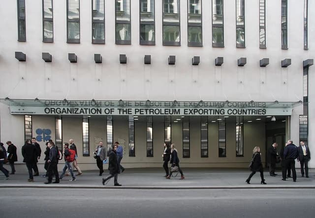 People walking on a sidewalk in front of the OPEC Headquarters building in Vienna.