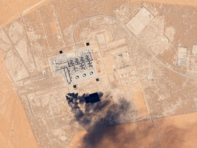 Aerial satellite view of the Khurais Oil Processing Facility in Saudi Arabia with smoke plume.