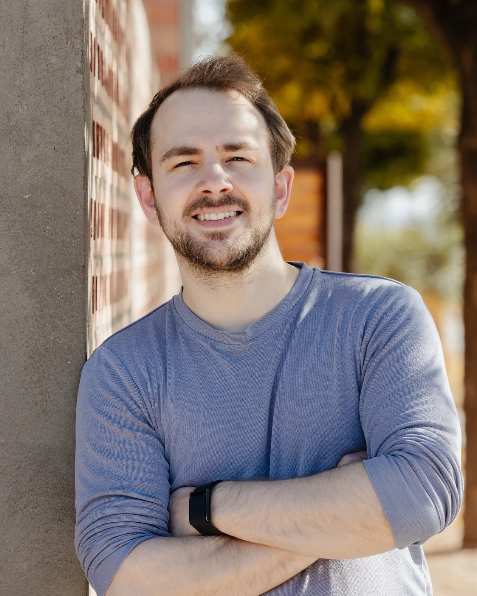 Devin Finzer, co-founder and CEO of OpenSea, standing with arms crossed next to a brick wall.