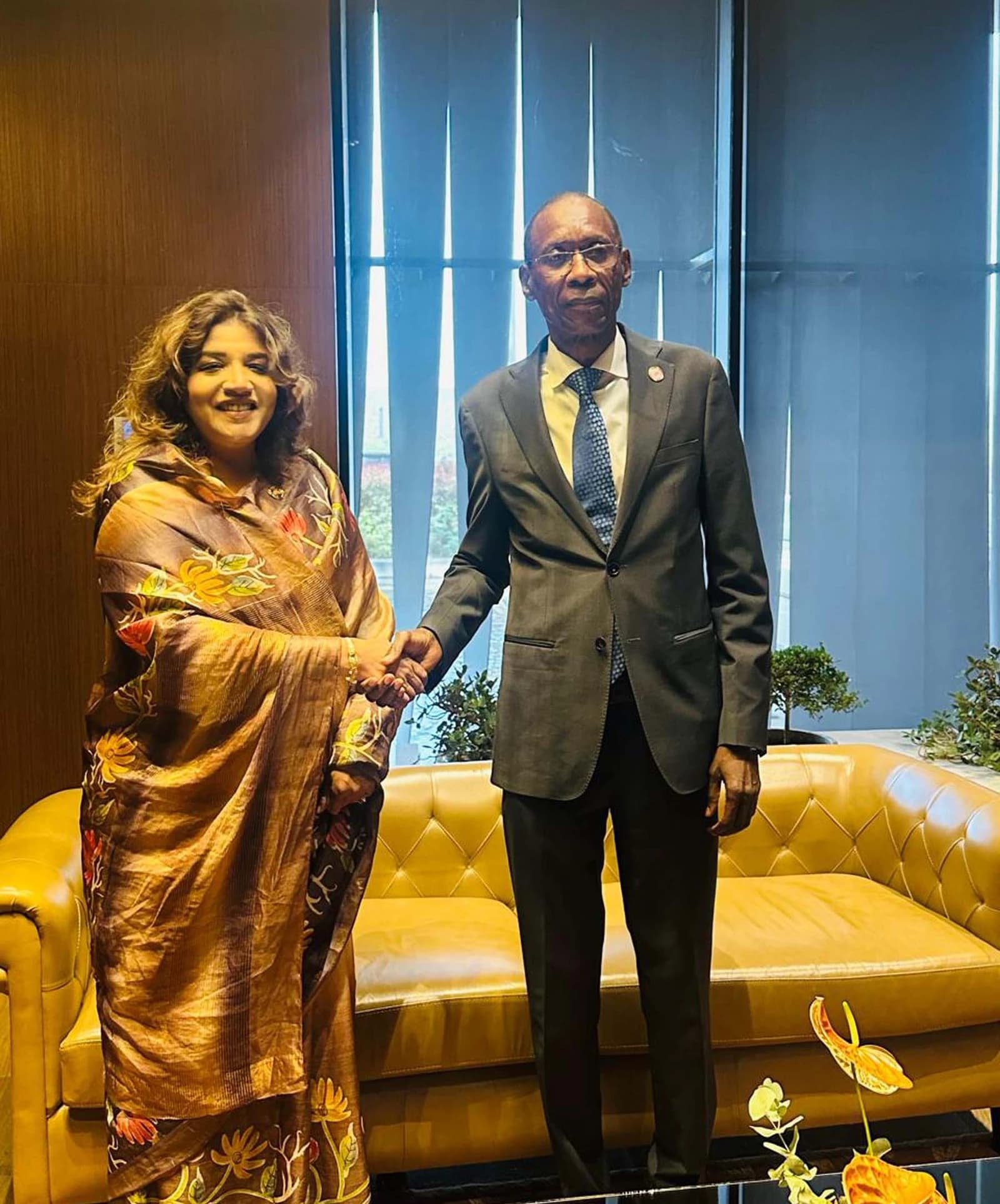 Shama Obaed Islam and Cheikh Niang shaking hands in an indoor setting.