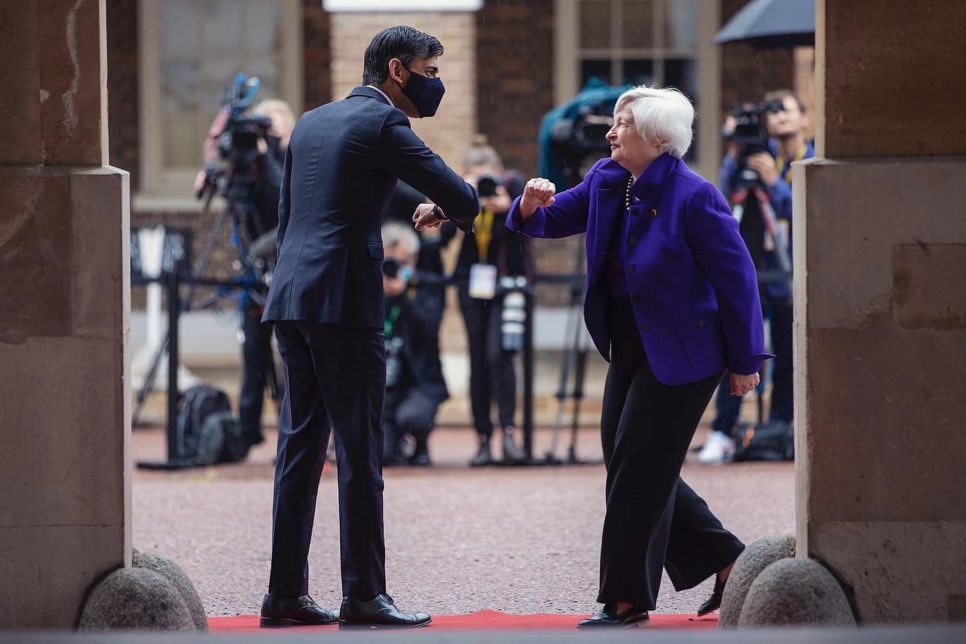 Rishi Sunak and Janet Yellen greet each other with elbow bumps outdoors.