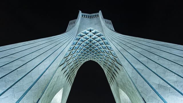 Azadi Tower, a monument and landmark, illuminated at night from a low-angle perspective.