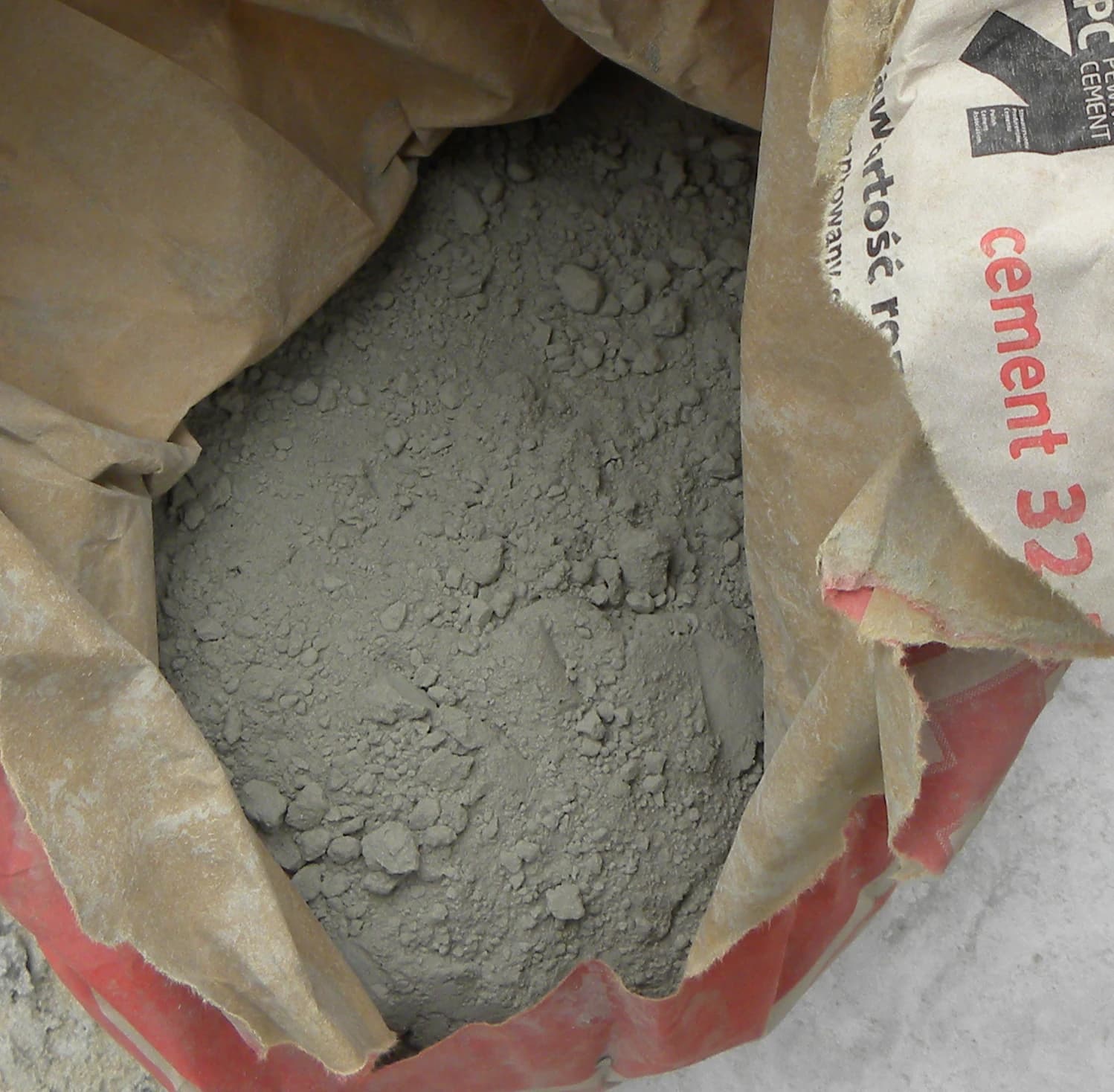 Close-up of a paper bag of cement, with the grey powder visible inside.