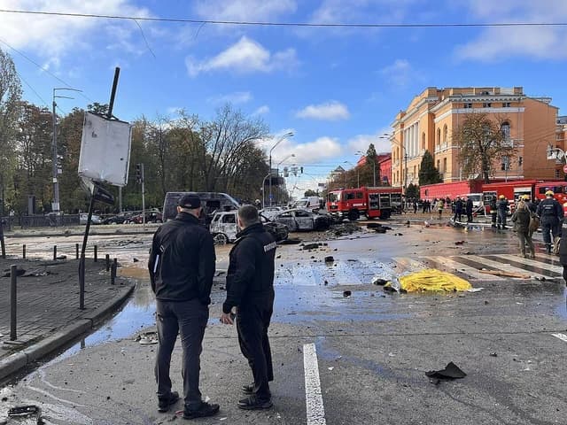 Emergency personnel and burnt vehicles on a street in Kyiv after shelling.